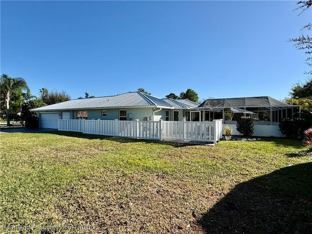 back of house with glass enclosure, a yard, fence, and metal roof