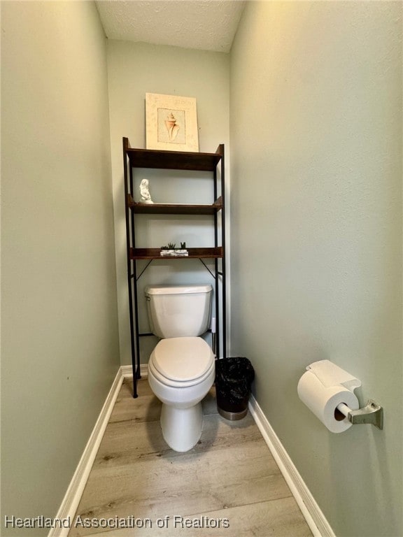 bathroom featuring toilet, wood finished floors, baseboards, and a textured ceiling