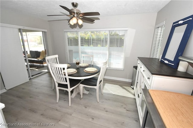 dining room with baseboards, a textured ceiling, ceiling fan, and light wood finished floors