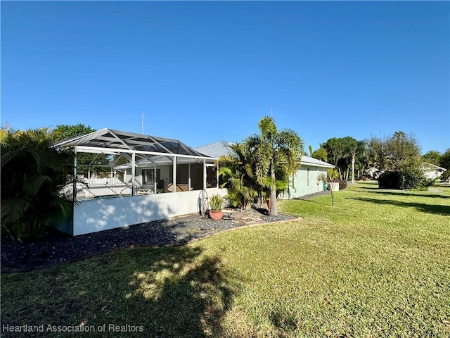 back of property with a yard and a lanai