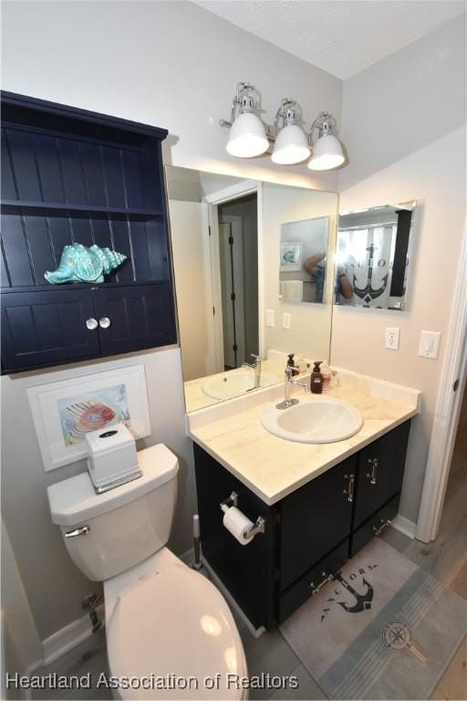 bathroom featuring toilet, vanity, and baseboards