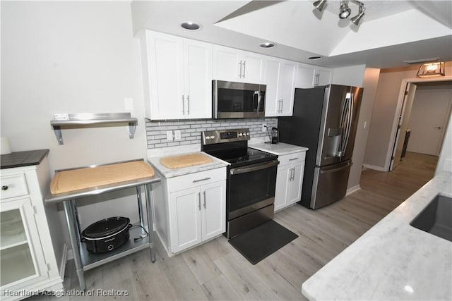 kitchen featuring backsplash, white cabinets, stainless steel appliances, and light countertops