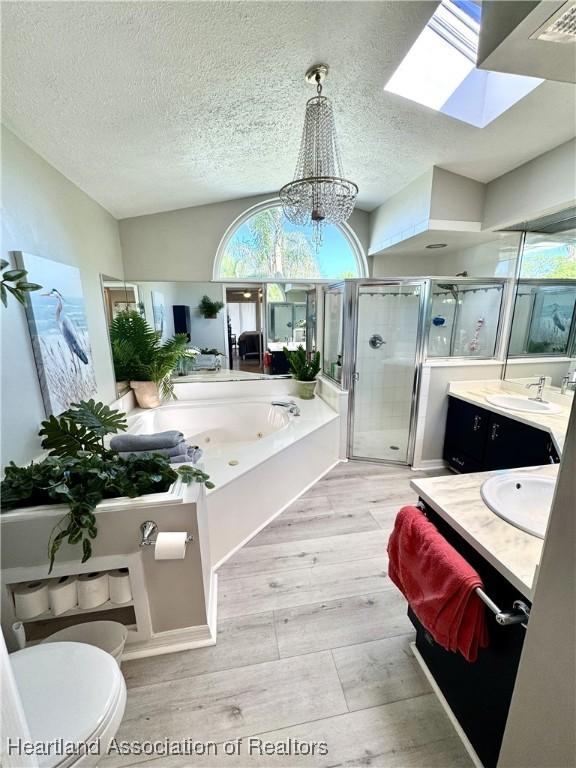 bathroom featuring a whirlpool tub, a textured ceiling, wood finished floors, a shower stall, and vanity