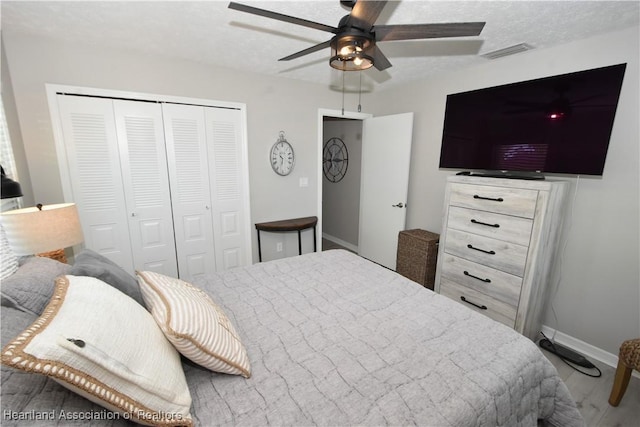 bedroom featuring visible vents, baseboards, ceiling fan, a closet, and a textured ceiling