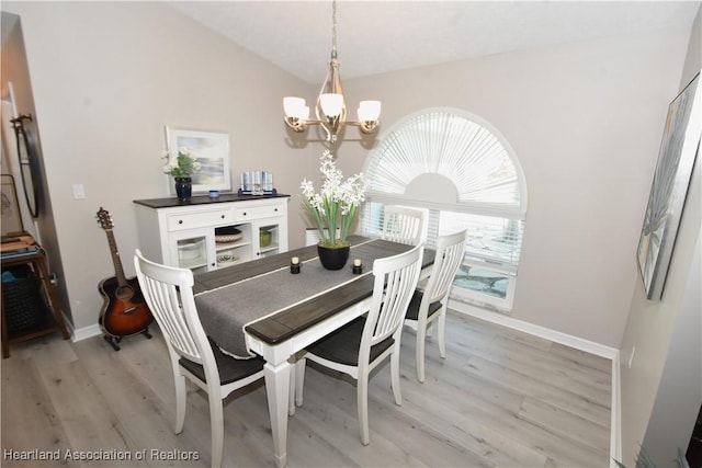 dining space with vaulted ceiling, a notable chandelier, light wood-style floors, and baseboards