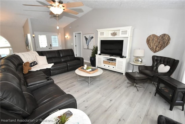 living room with ceiling fan, plenty of natural light, light wood-style flooring, and vaulted ceiling