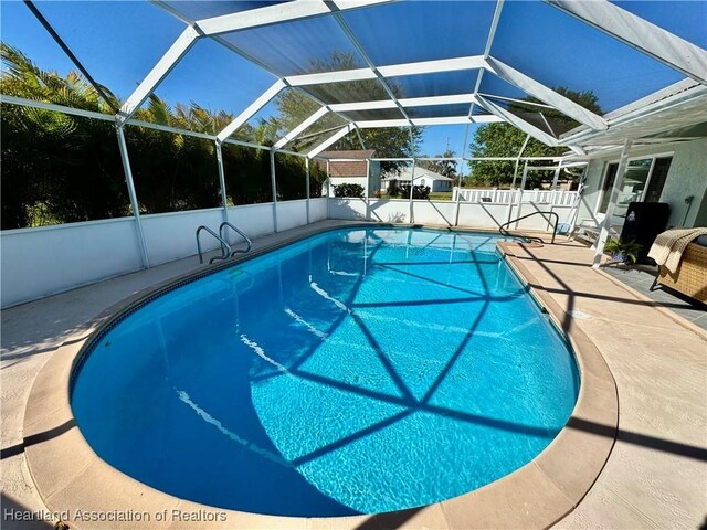 view of swimming pool featuring glass enclosure, a patio, and a fenced in pool