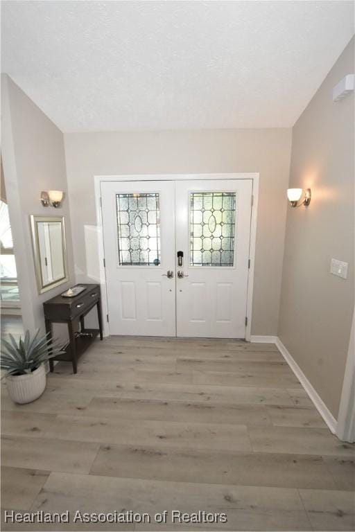 entrance foyer with light wood finished floors, french doors, and baseboards