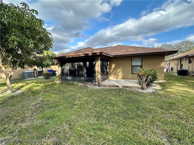 rear view of property featuring a lawn, a sunroom, a patio, and central AC unit