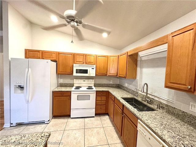 kitchen with sink, light stone counters, vaulted ceiling, white appliances, and light tile patterned floors