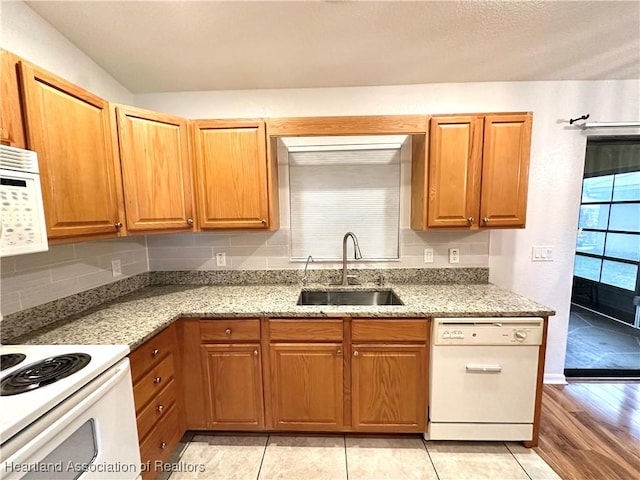 kitchen featuring decorative backsplash, sink, white appliances, and light hardwood / wood-style flooring