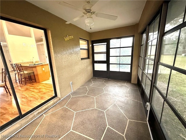 unfurnished sunroom featuring ceiling fan