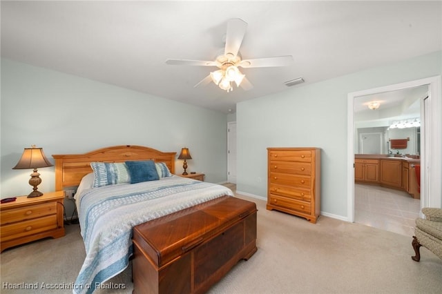 bedroom featuring visible vents, ensuite bathroom, a ceiling fan, baseboards, and light colored carpet