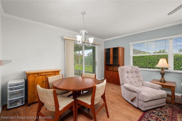 dining space with a notable chandelier, crown molding, light wood-type flooring, and baseboards