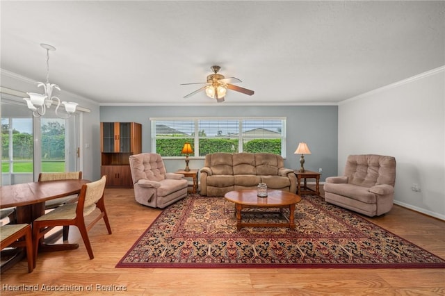 living area featuring baseboards, light wood-style floors, ornamental molding, and ceiling fan with notable chandelier