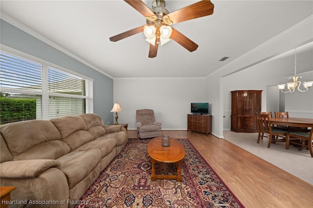 living area featuring visible vents, ceiling fan with notable chandelier, wood finished floors, and ornamental molding