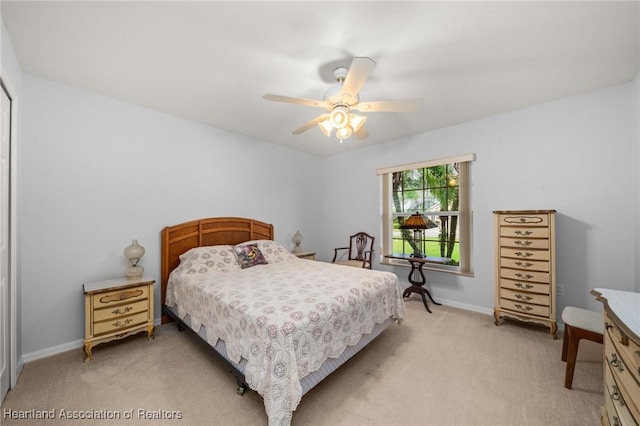 bedroom with a ceiling fan, baseboards, and light carpet