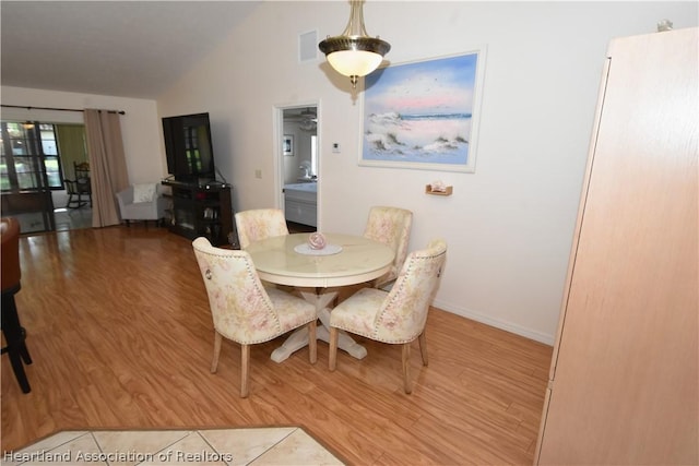 dining area with light hardwood / wood-style floors and vaulted ceiling