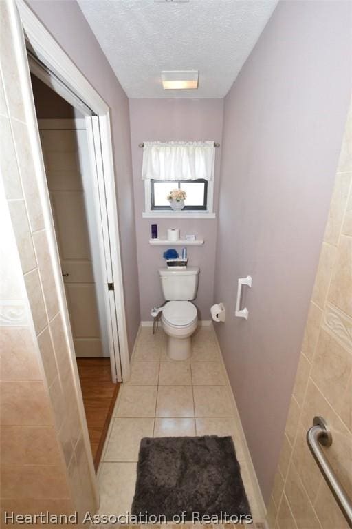 bathroom featuring tile patterned flooring, a textured ceiling, and toilet