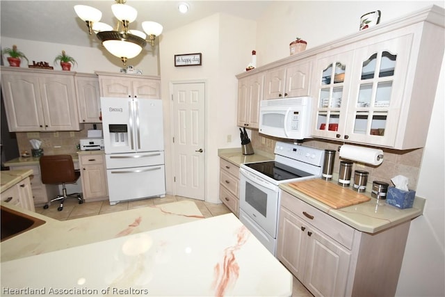 kitchen with white appliances, tasteful backsplash, a notable chandelier, and light tile patterned flooring