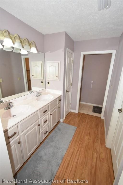 bathroom featuring hardwood / wood-style floors, vanity, and a textured ceiling