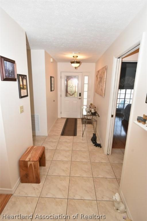 doorway with plenty of natural light, light tile patterned flooring, and a textured ceiling