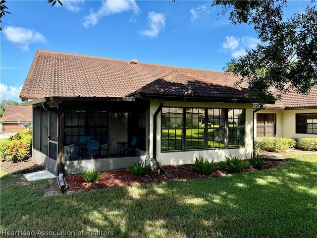 rear view of house with a lawn and a sunroom