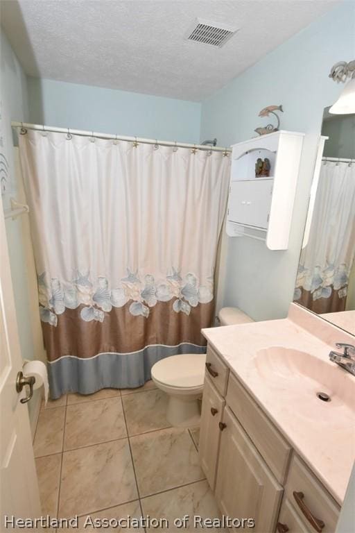 bathroom with tile patterned floors, vanity, a textured ceiling, and toilet