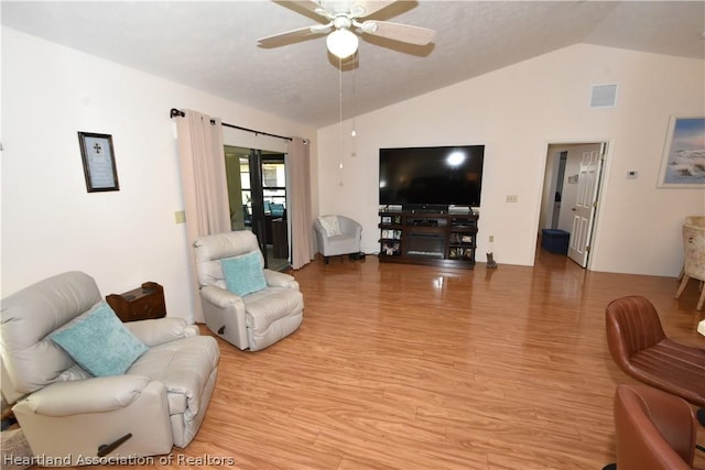 living room featuring ceiling fan, light hardwood / wood-style floors, and vaulted ceiling