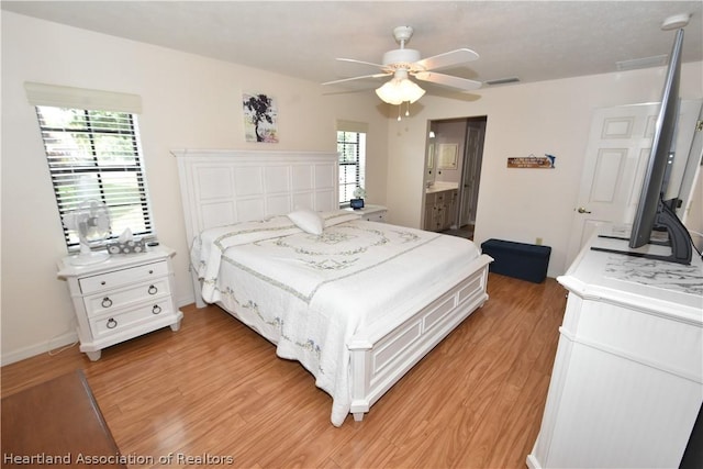 bedroom with ceiling fan, ensuite bath, light wood-type flooring, and multiple windows