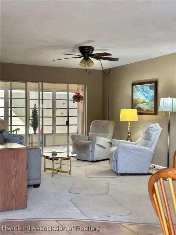 living area featuring a ceiling fan, light colored carpet, and a textured ceiling