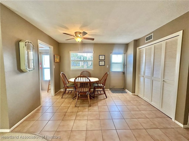 dining space featuring light tile patterned flooring, ceiling fan, visible vents, and baseboards