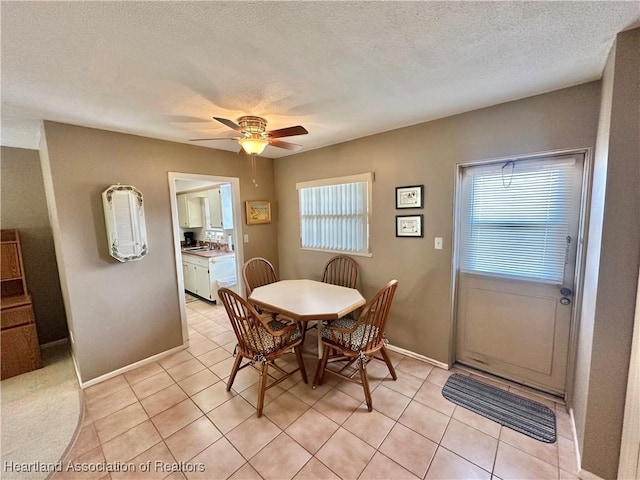 dining room with light tile patterned floors, a textured ceiling, a ceiling fan, and baseboards