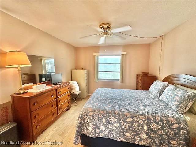 bedroom with multiple windows, a ceiling fan, and light wood-style floors