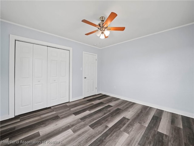 unfurnished bedroom with crown molding, dark wood-type flooring, ceiling fan, and a closet