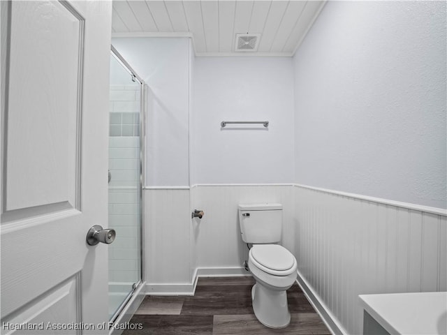 bathroom featuring wood-type flooring, a shower with door, and toilet