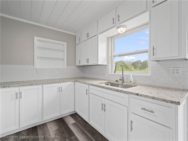 kitchen with light stone counters, sink, ornamental molding, and white cabinets