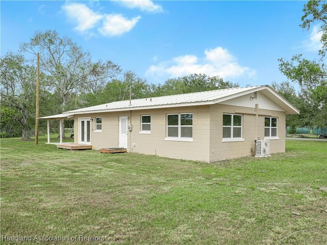 rear view of house with ac unit and a lawn