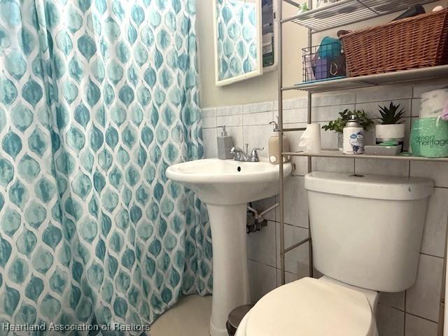 9590 NW 22nd Ave, Miami, FL 33147 - bathroom featuring a shower with curtain, tile walls, and toilet