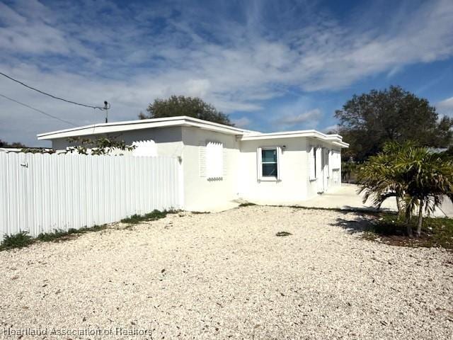 rear view of property featuring fence and stucco siding