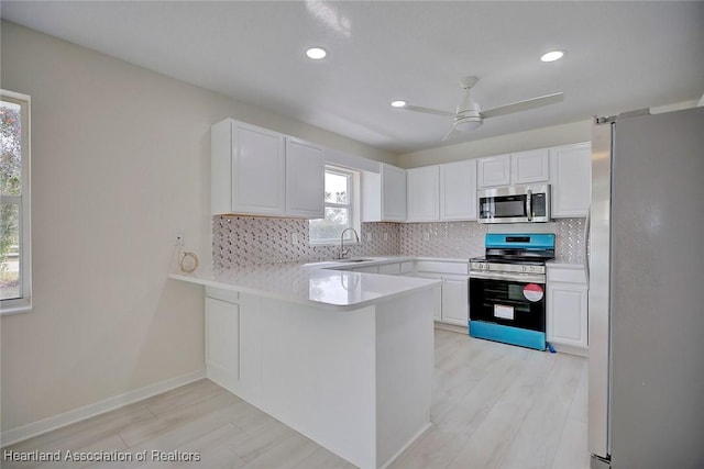 kitchen featuring white cabinetry, appliances with stainless steel finishes, kitchen peninsula, and backsplash