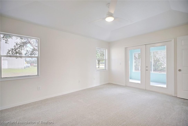 empty room featuring french doors, ceiling fan, carpet flooring, and a raised ceiling