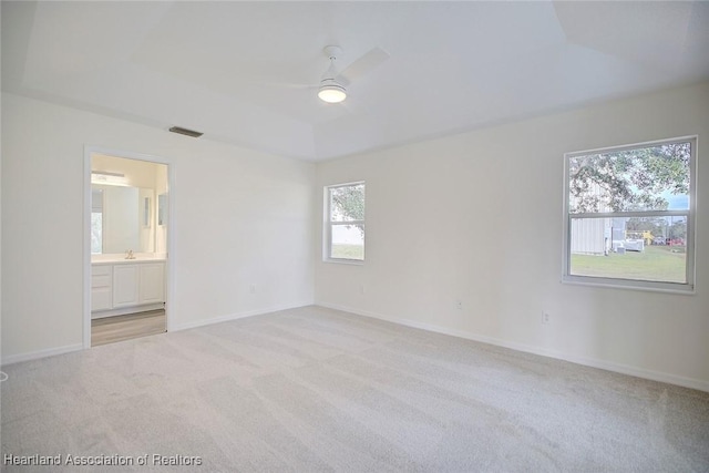 carpeted spare room with a raised ceiling and ceiling fan