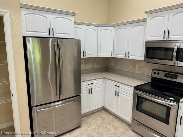 kitchen featuring white cabinets, decorative backsplash, stainless steel appliances, and light tile patterned flooring