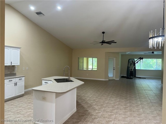 kitchen featuring ceiling fan, a kitchen island with sink, sink, white cabinets, and lofted ceiling