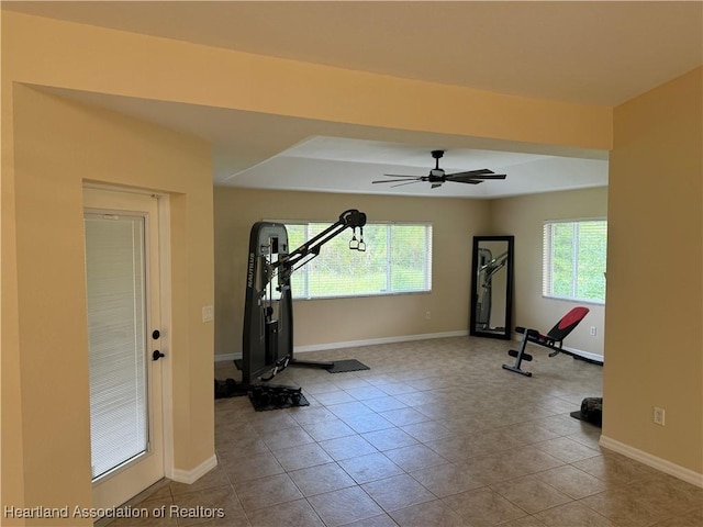 workout area featuring ceiling fan, light tile patterned flooring, and a wealth of natural light