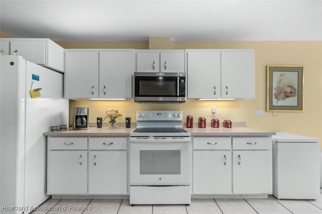 kitchen with white cabinetry, light tile patterned flooring, and white appliances