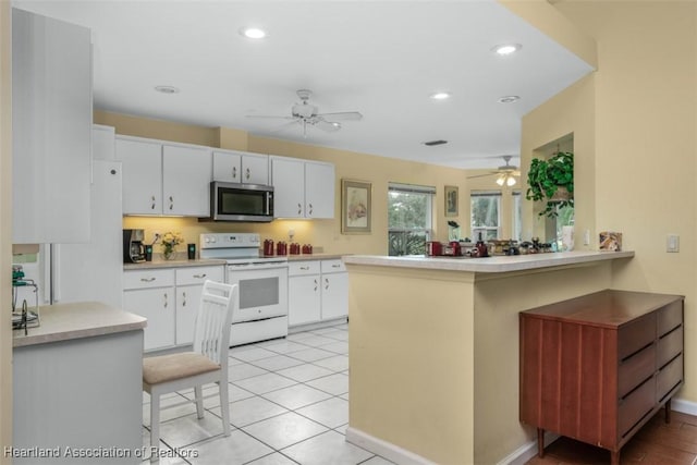 kitchen featuring white cabinets, electric range, kitchen peninsula, and light tile patterned flooring