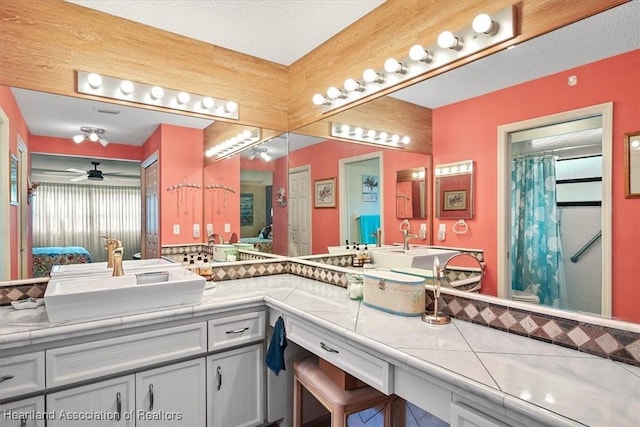 bathroom featuring ceiling fan, vanity, a textured ceiling, and a shower with shower curtain