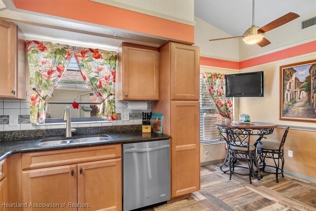 kitchen with a wealth of natural light, dark stone counters, ceiling fan, sink, and dishwasher